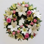 Delicate wreath of lilies and roses in pinks and whites.