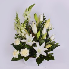 White seasonal flowers, including Oriental lilies, roses and carnations, in a ceramic pot.