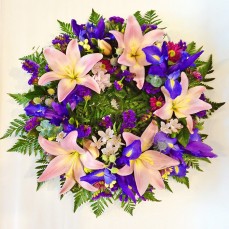 Wreath of pink lilies and iris with seasonal blooms.